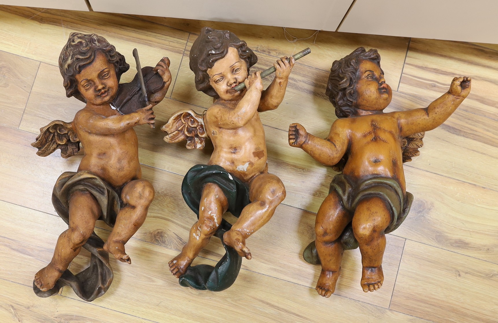 A trio of plaster cherubs with instruments